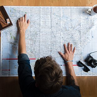 Eine Person gebeugt über eine USA-Karte ©Brady Knoll / pexels.com