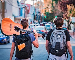 Zwei junge Männer mit Rucksack und Gitarre ©Austin Distel / unsplash.com