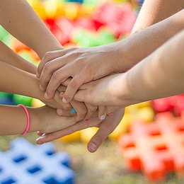 Kinderhände liegen übereinander vor buntem Hintergrund © Jarmoluk / pixabay.com