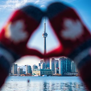 Wollhandschuhe mit dem kanadischen Ahornblatt rahmen die Skyline von Toronto ©Lisa Simpson / pexels.com